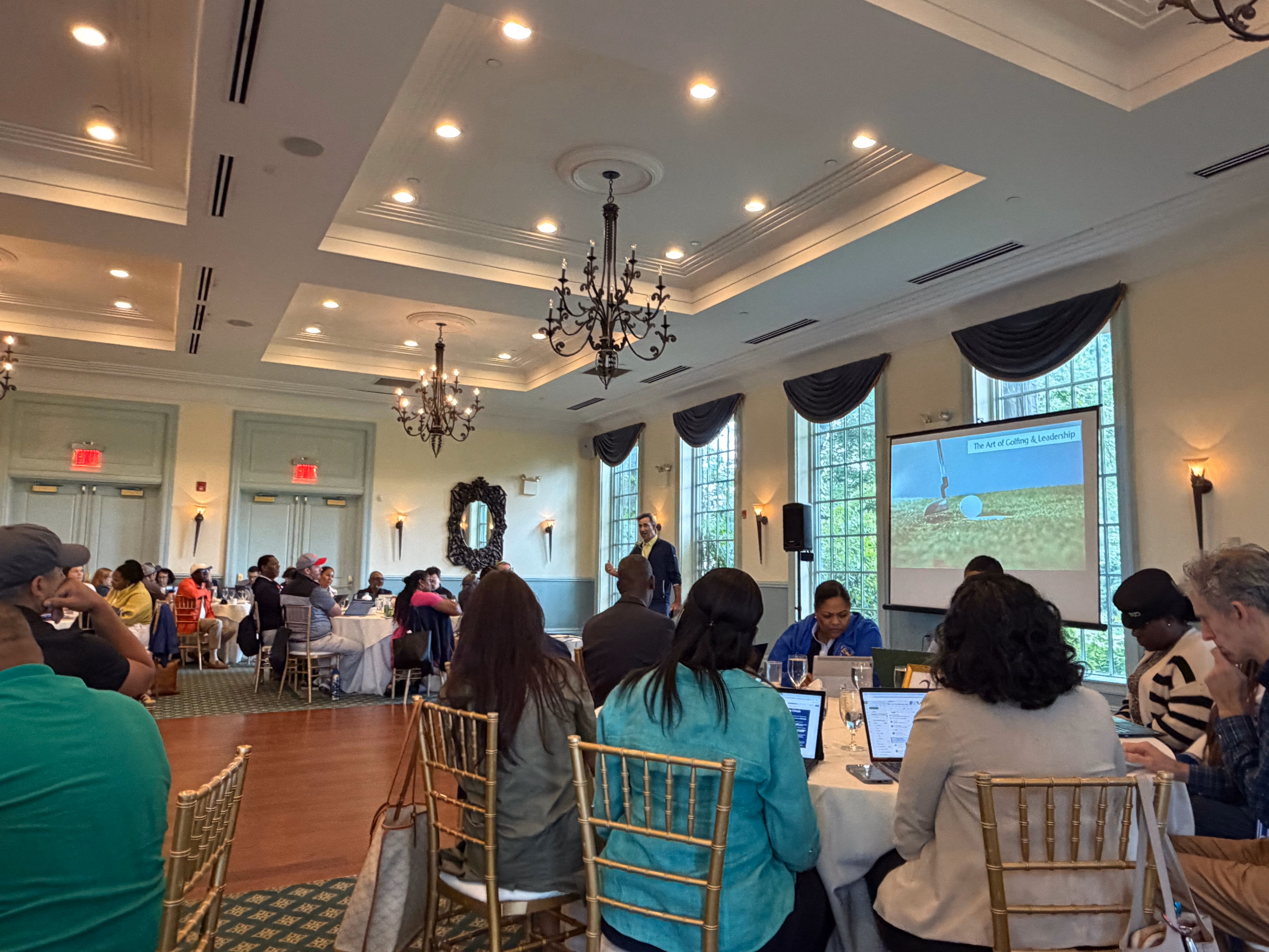 Attendees seated at tables during Art of Golfing and Leadership presentation