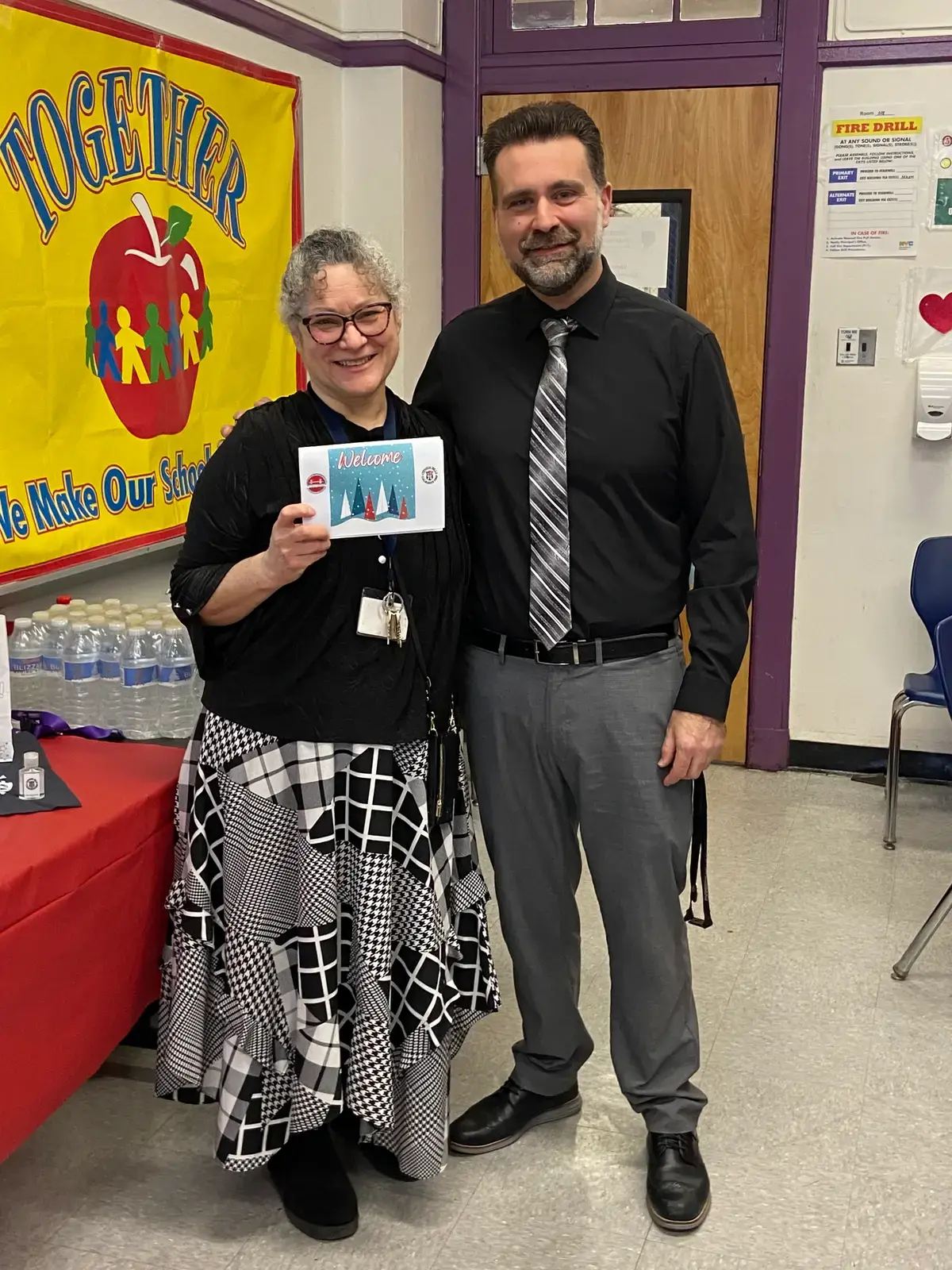 Staff member holding a holiday card posing with a colleague