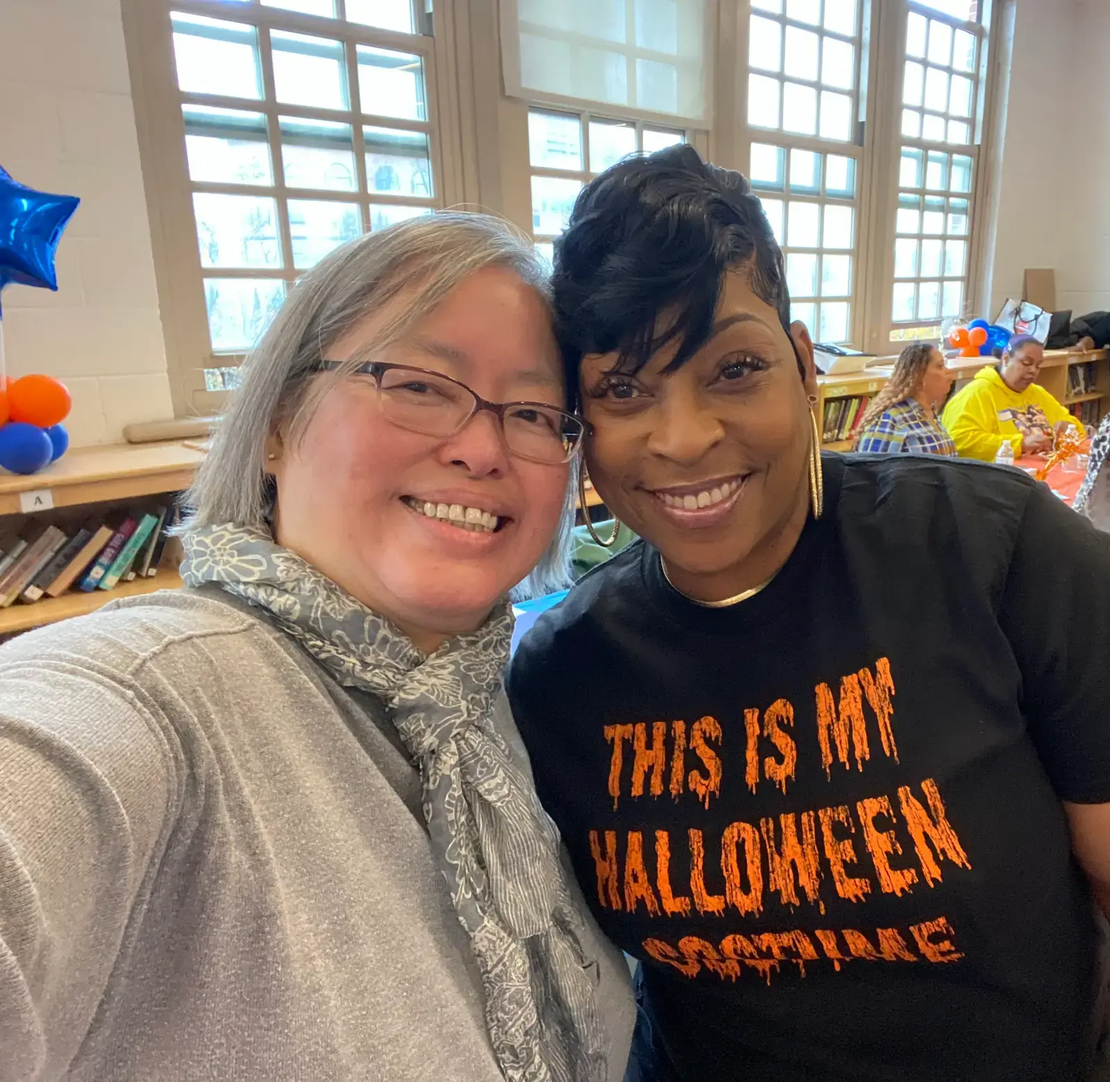 Two staff members smiling together at a school Halloween event