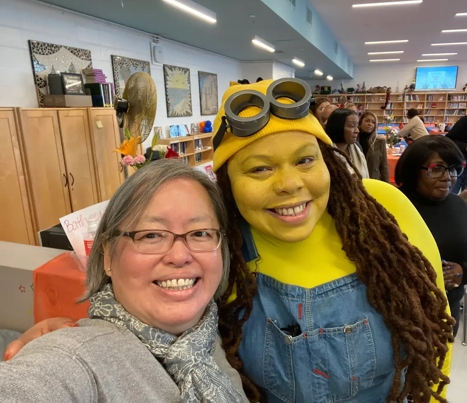 Two staff members smiling at school event one in Minion costume