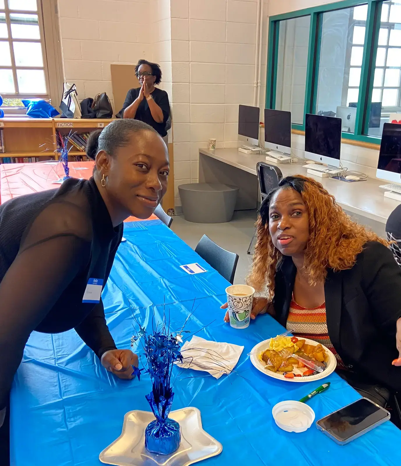 Two adults smiling together at a school library event table