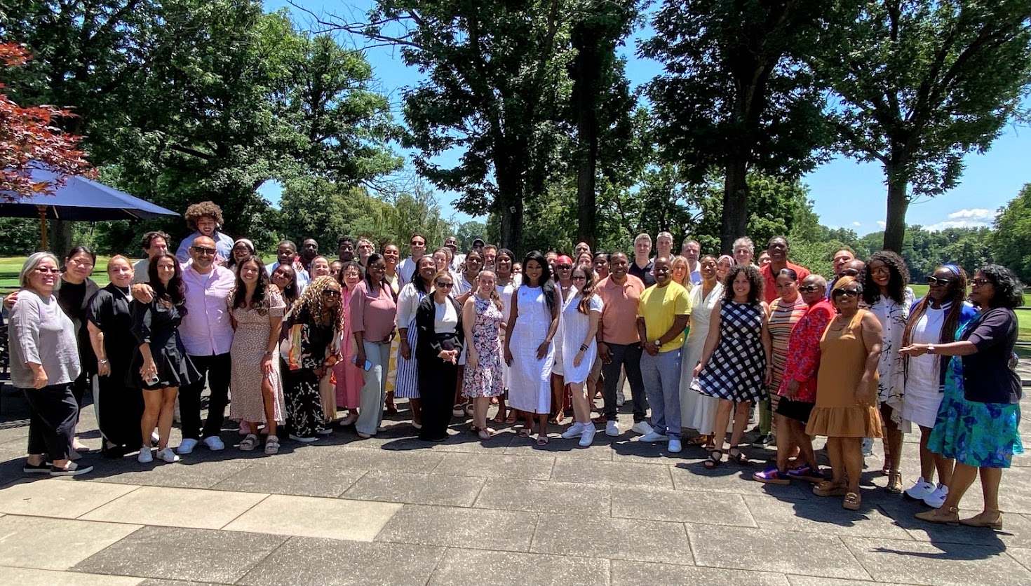 Large group of staff posing outdoors on sunny day