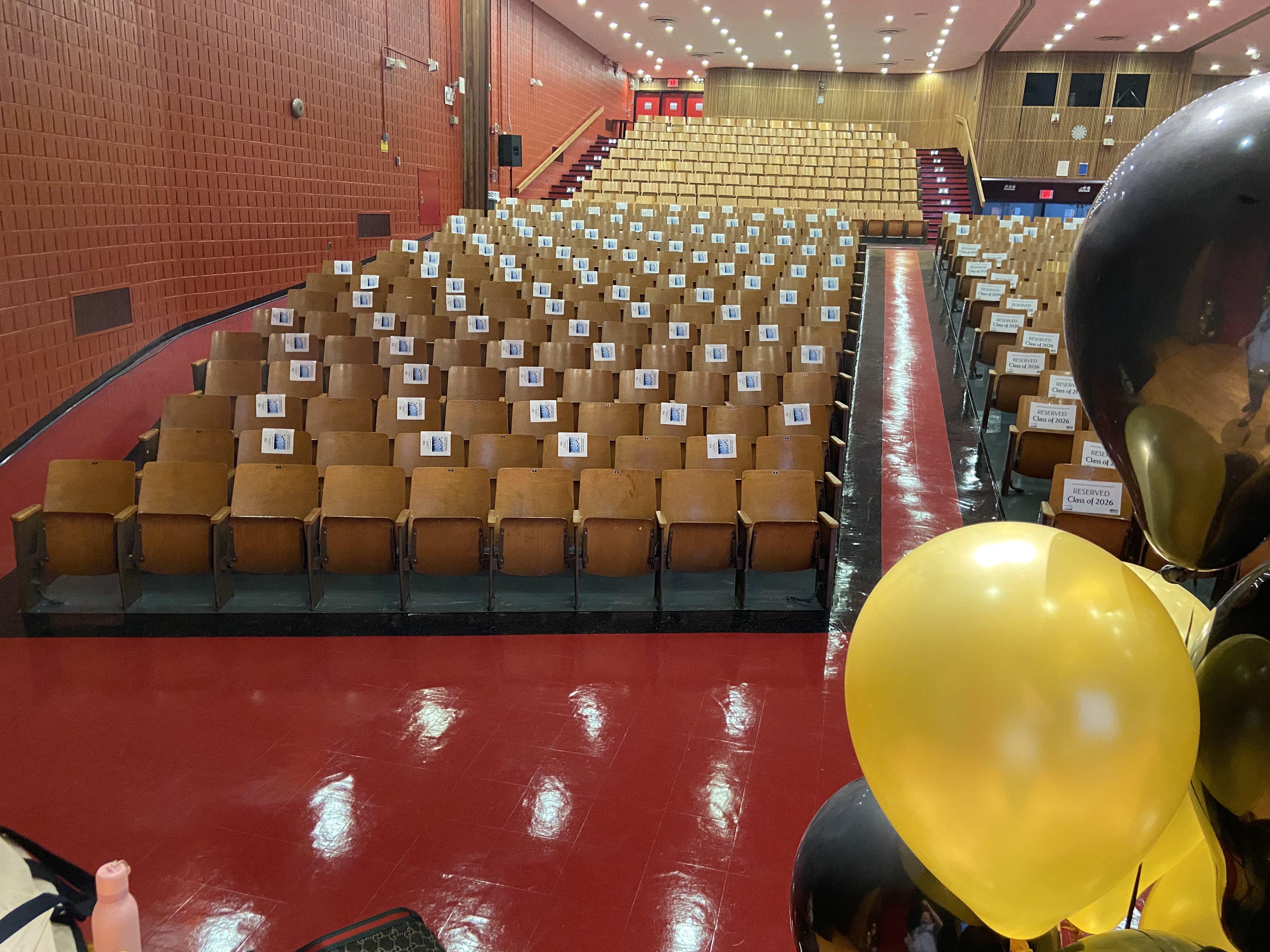 School auditorium set up with reserved seats and graduation balloons