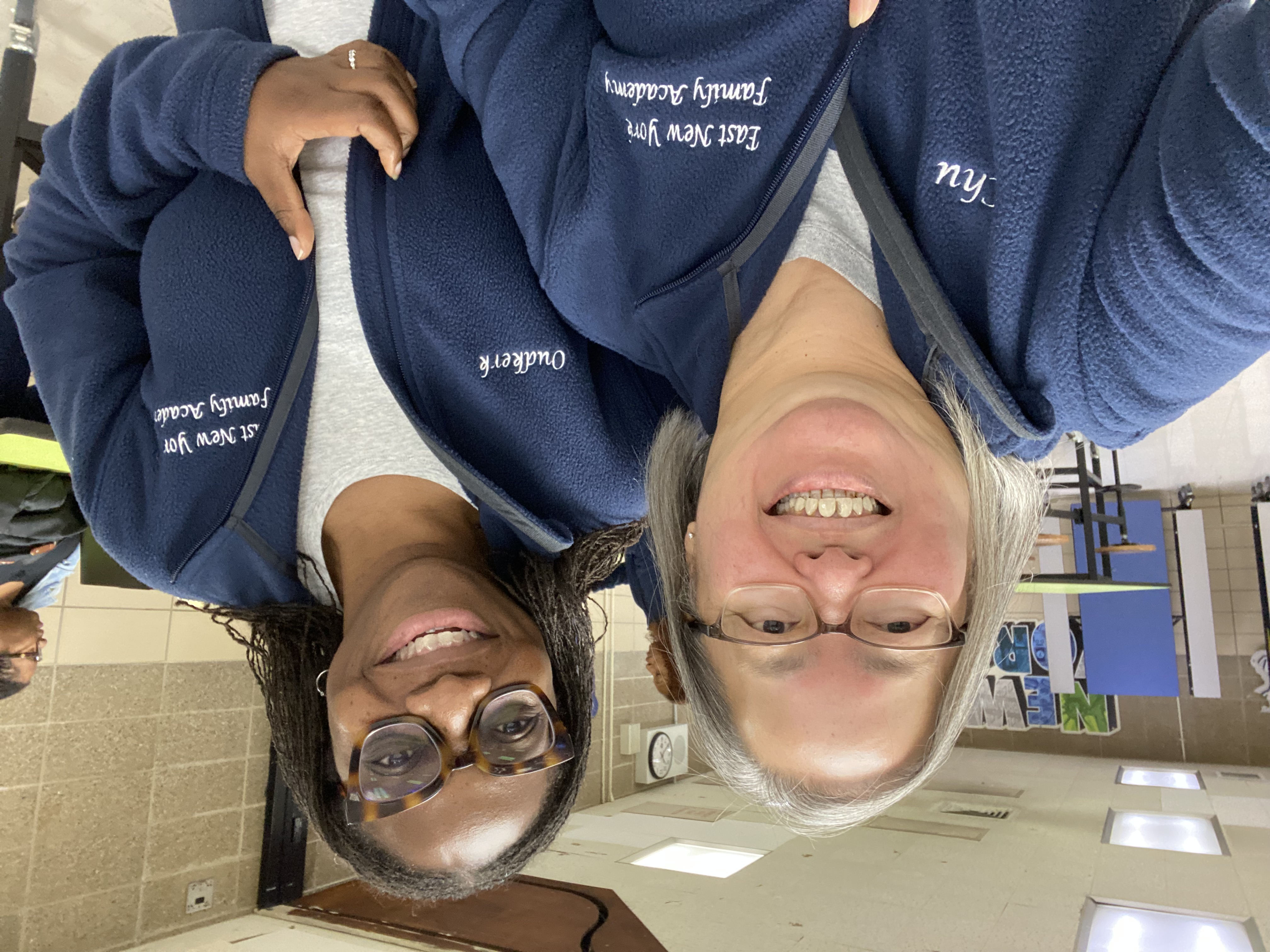 Two staff members smiling in East New York Family Academy fleece jackets