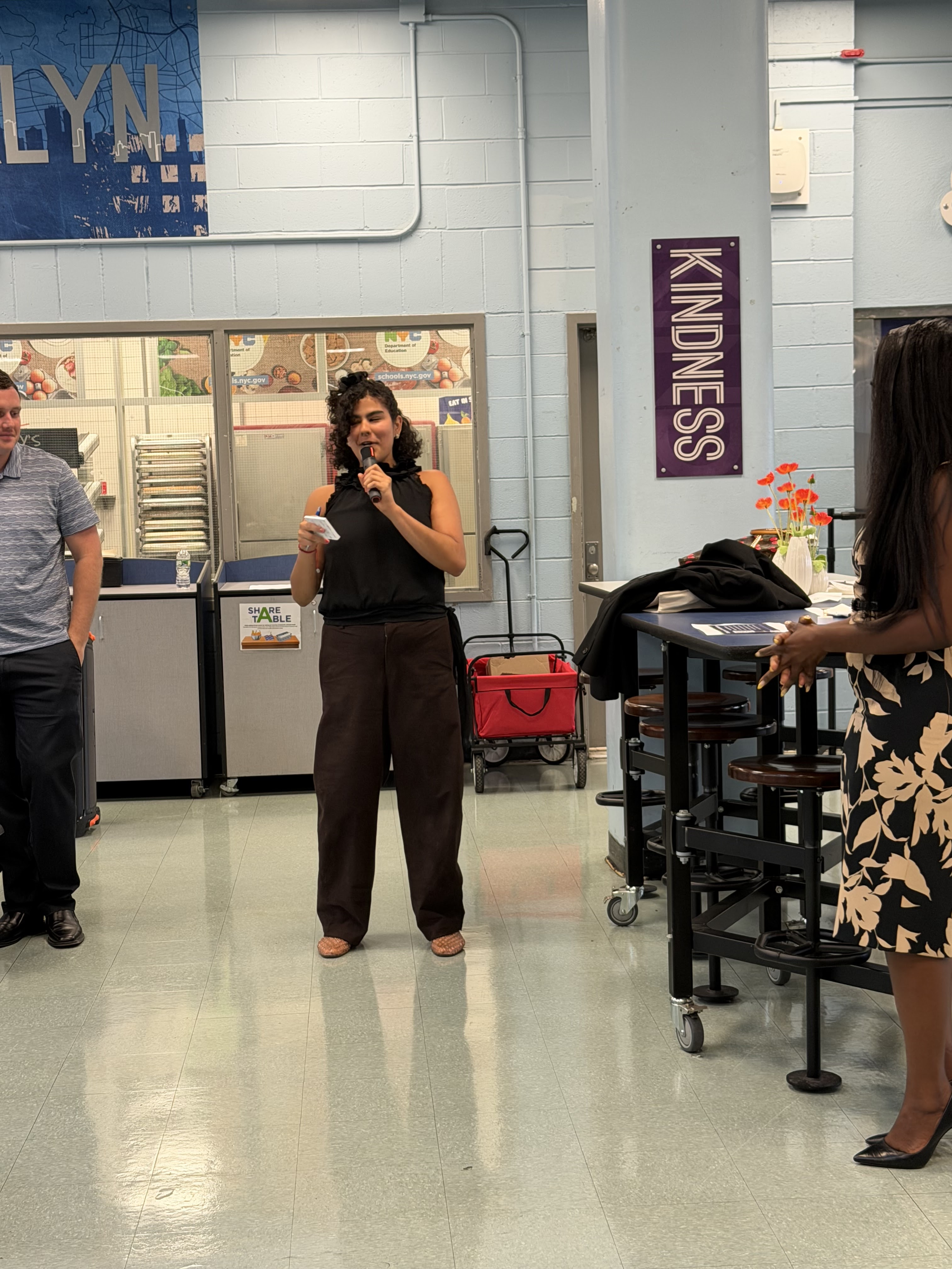 Woman speaking into microphone at school cafeteria event