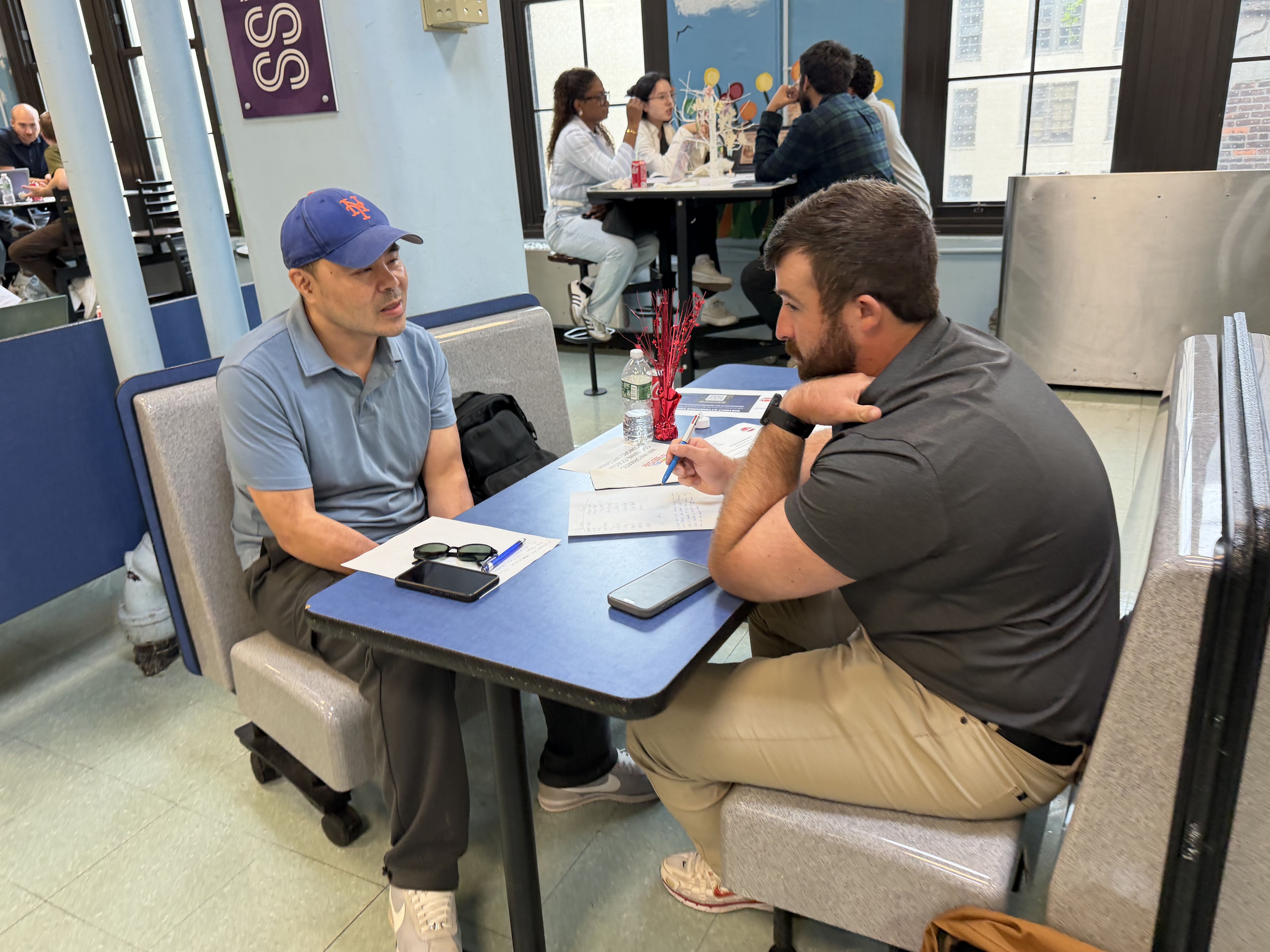 Two people meeting at a table reviewing documents in school cafeteria