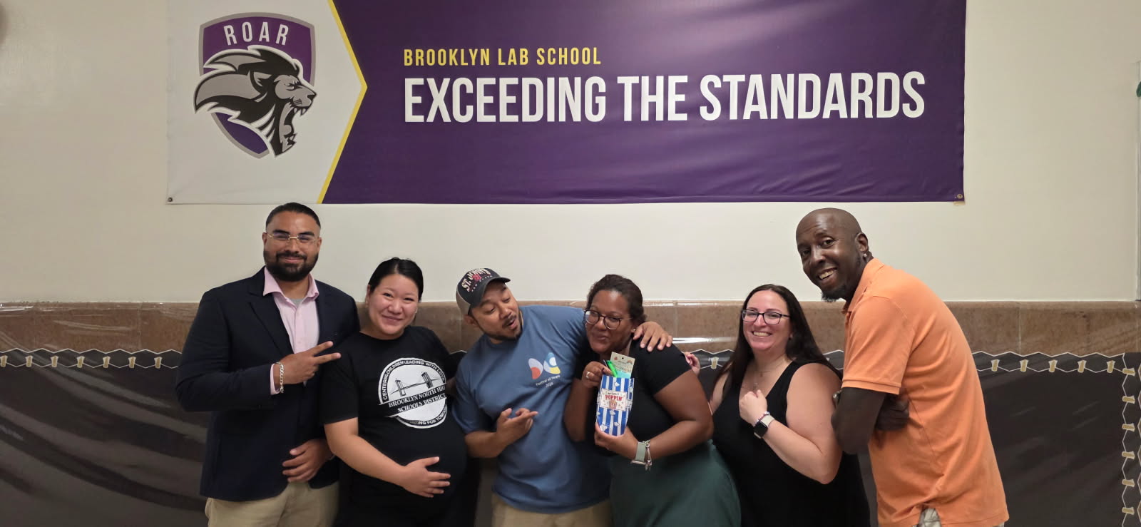 Six Brooklyn Lab School staff members posing together under school banner