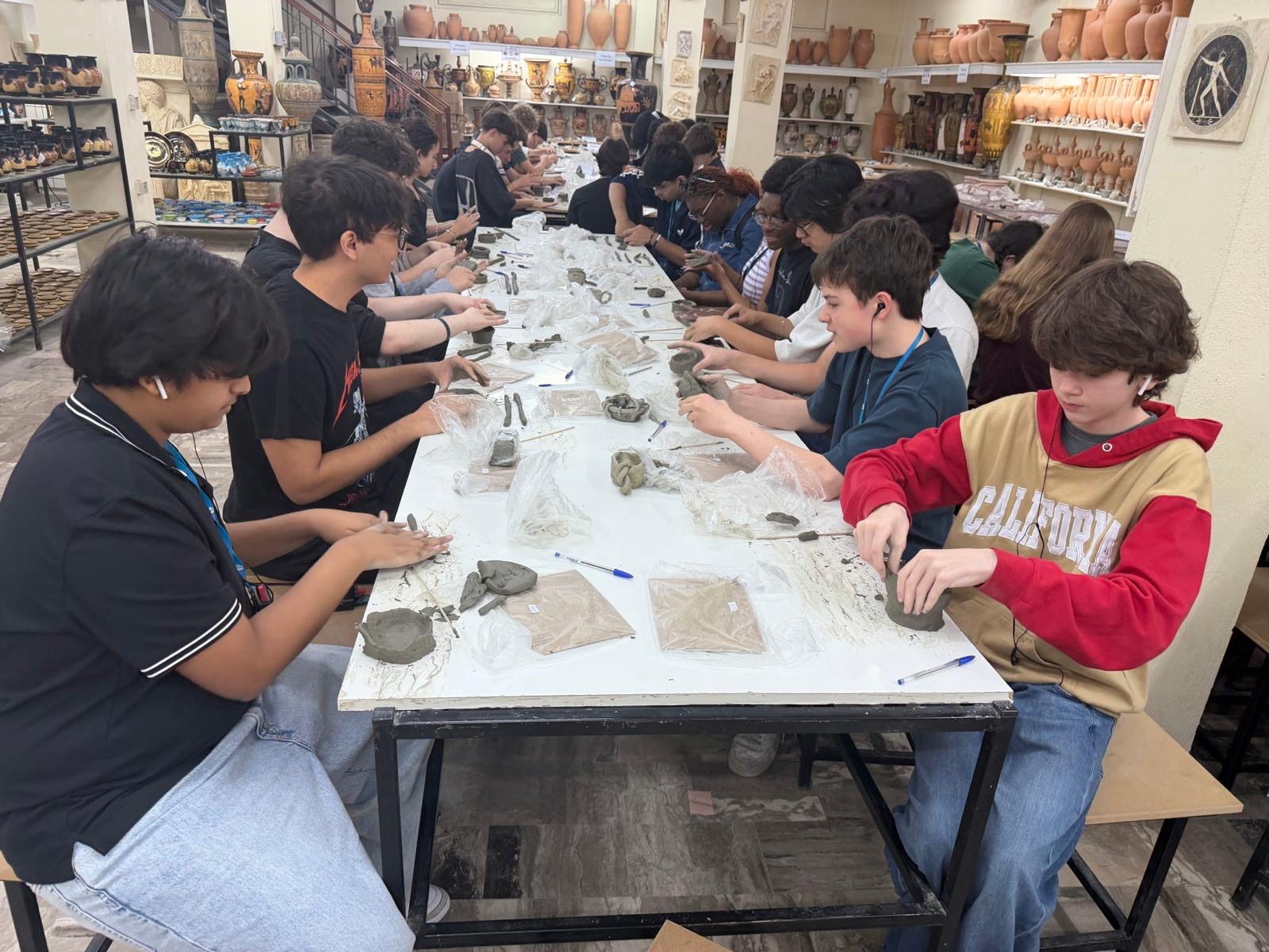 Students working with clay at long table in pottery studio