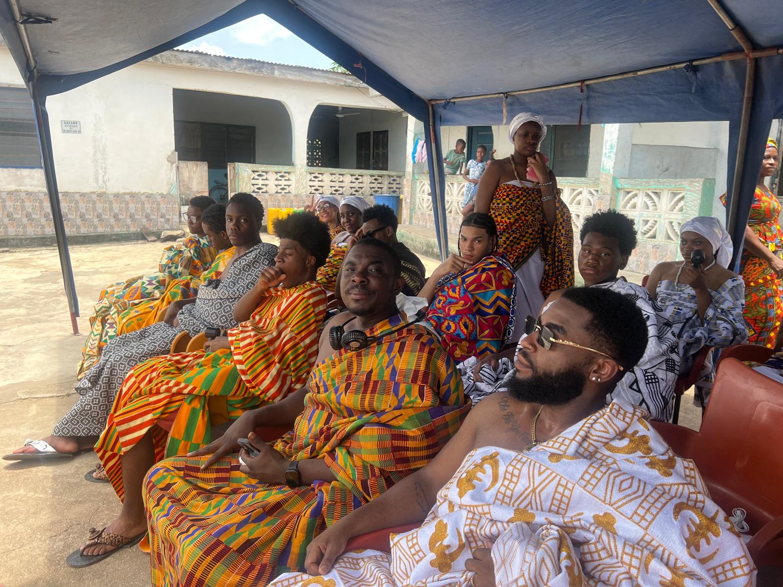 Students and community members seated in traditional Ghanaian kente cloth attire