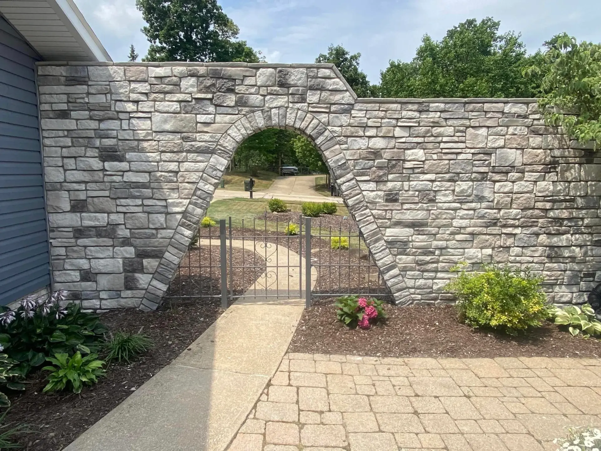 stone wall with fence to front of house