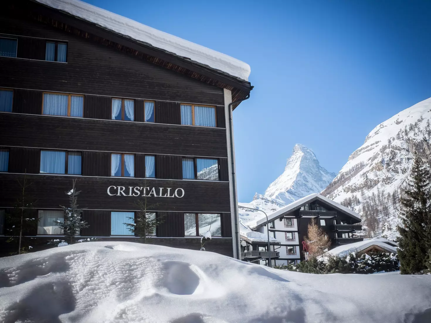Schneebedeckte Chalets unter klarem Himmel mit Matterhorn im Hintergrund.