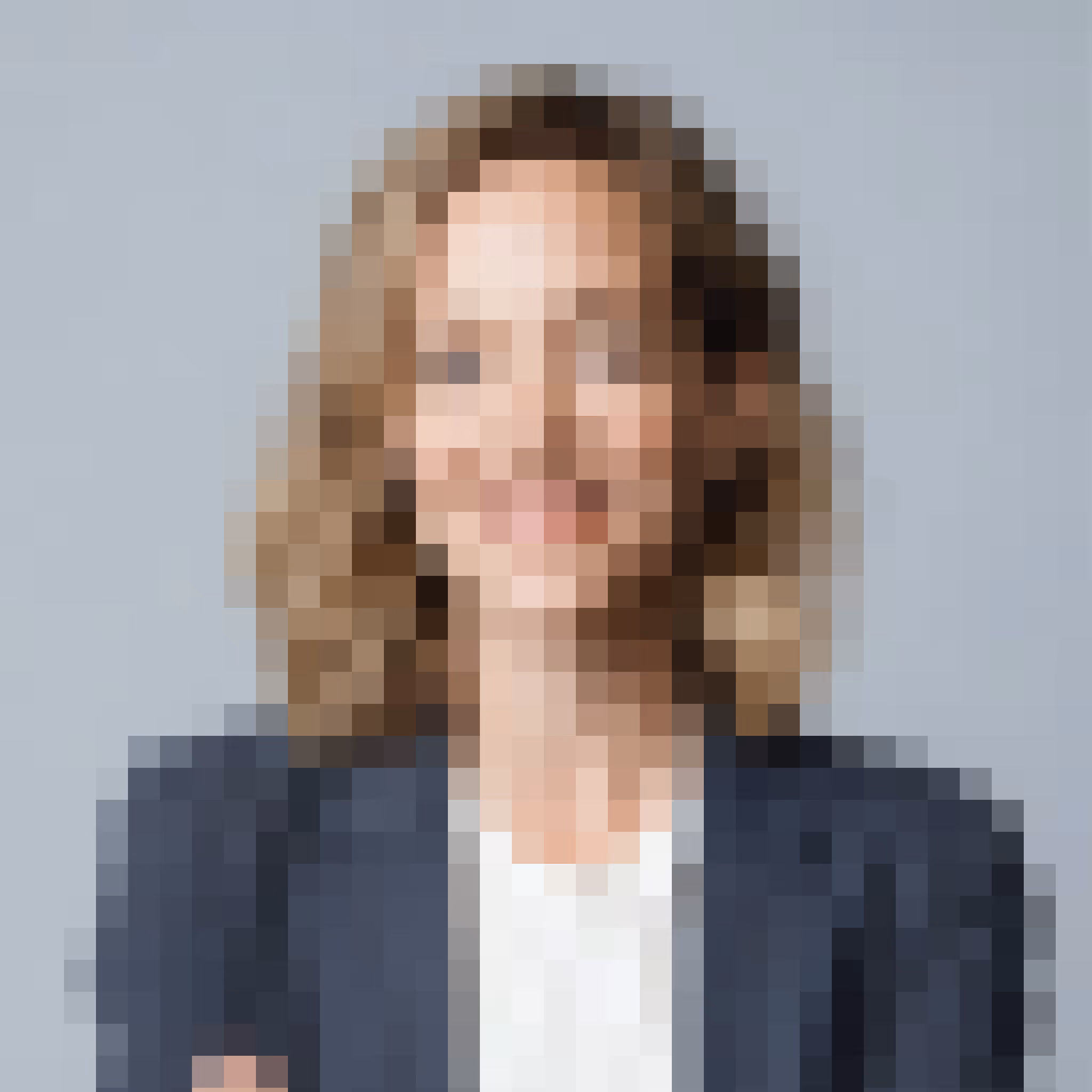 Portrait of a smiling woman with shoulder-length curly hair wearing a dark blazer and white top.