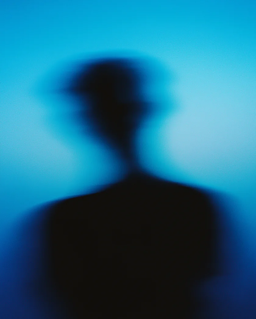 Blurry silhouette of a person against a blue background with indistinct features.
