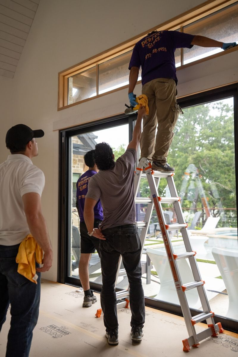 Post-construction cleaning crew detailing large glass doors before final handoff