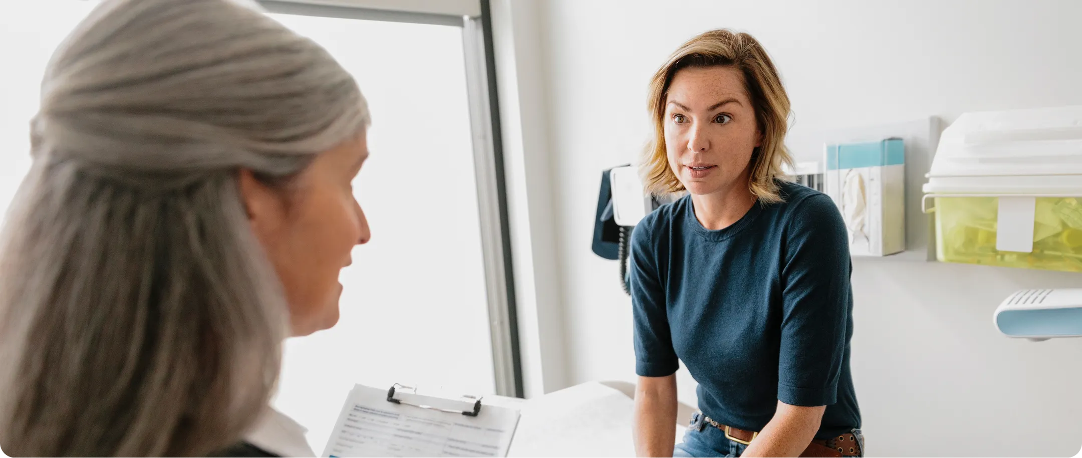 Smiling man with beard playfully interacting with a happy child sitting on a kitchen counter, with two laughing children in the background.