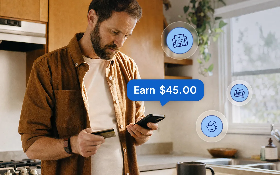 Man paying with a card while checking his phone in a kitchen, with a badge showing Earn $45.00.