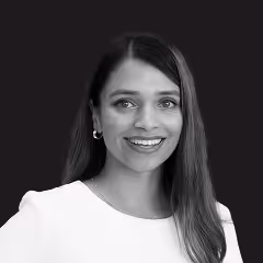 Smiling woman with long hair wearing a white top against a dark background.