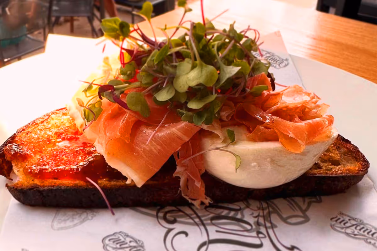 Close-up of bubbling pepperoni pizza slices with melted cheese and golden crust on a black surface.