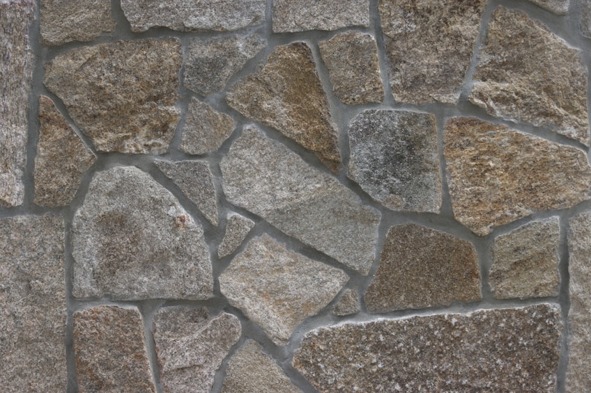Close-up of a stone wall with irregular brown and gray stones set in gray mortar.