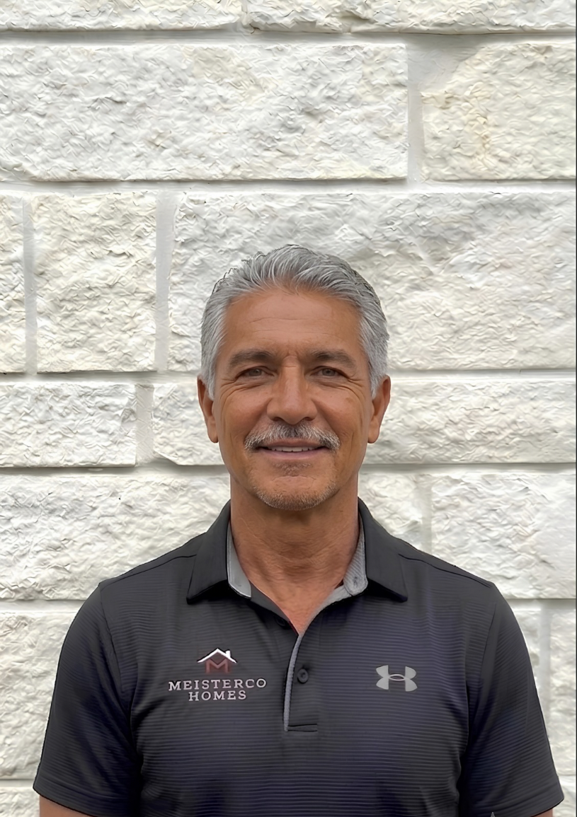 Smiling middle-aged man with gray hair and mustache wearing black Meisterco Homes polo shirt.