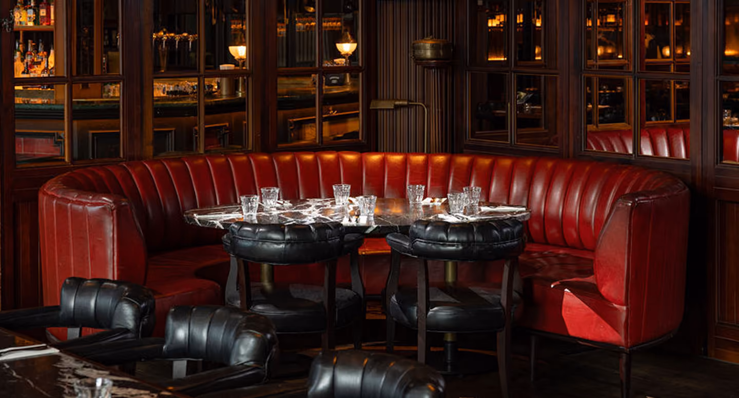 Empty red booth seating and dining tables in a dimly lit restaurant interior