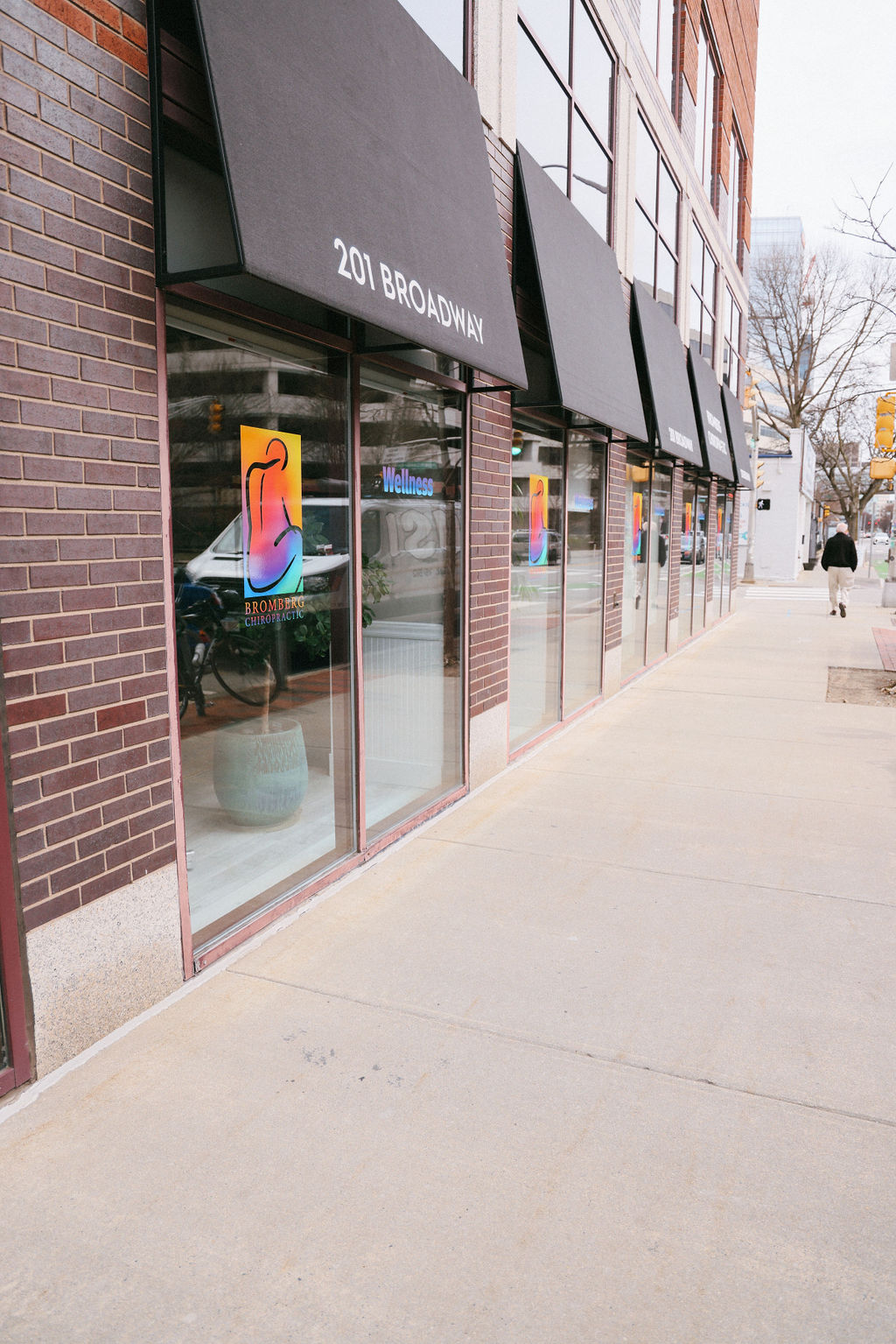 Building storefront with black awnings displaying 201 BROADWAY and Bromberg Chiropractic logo on windows.