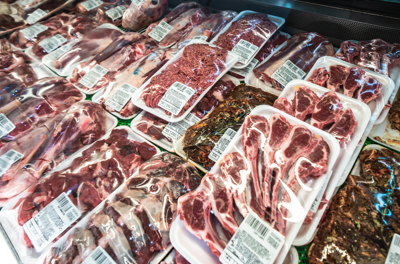 Aerial view of a busy urban intersection with multiple vehicles, commercial buildings, parking lots, and surrounding residential areas.