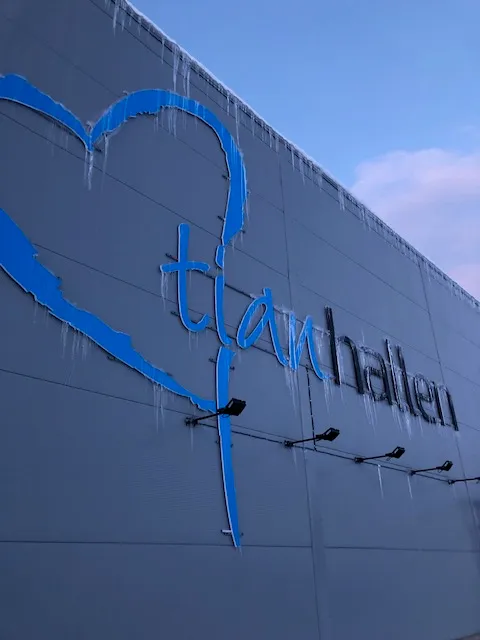 Blå og svart Tianhallen-skilt på en vegg med istapper som henger ned fra taket.