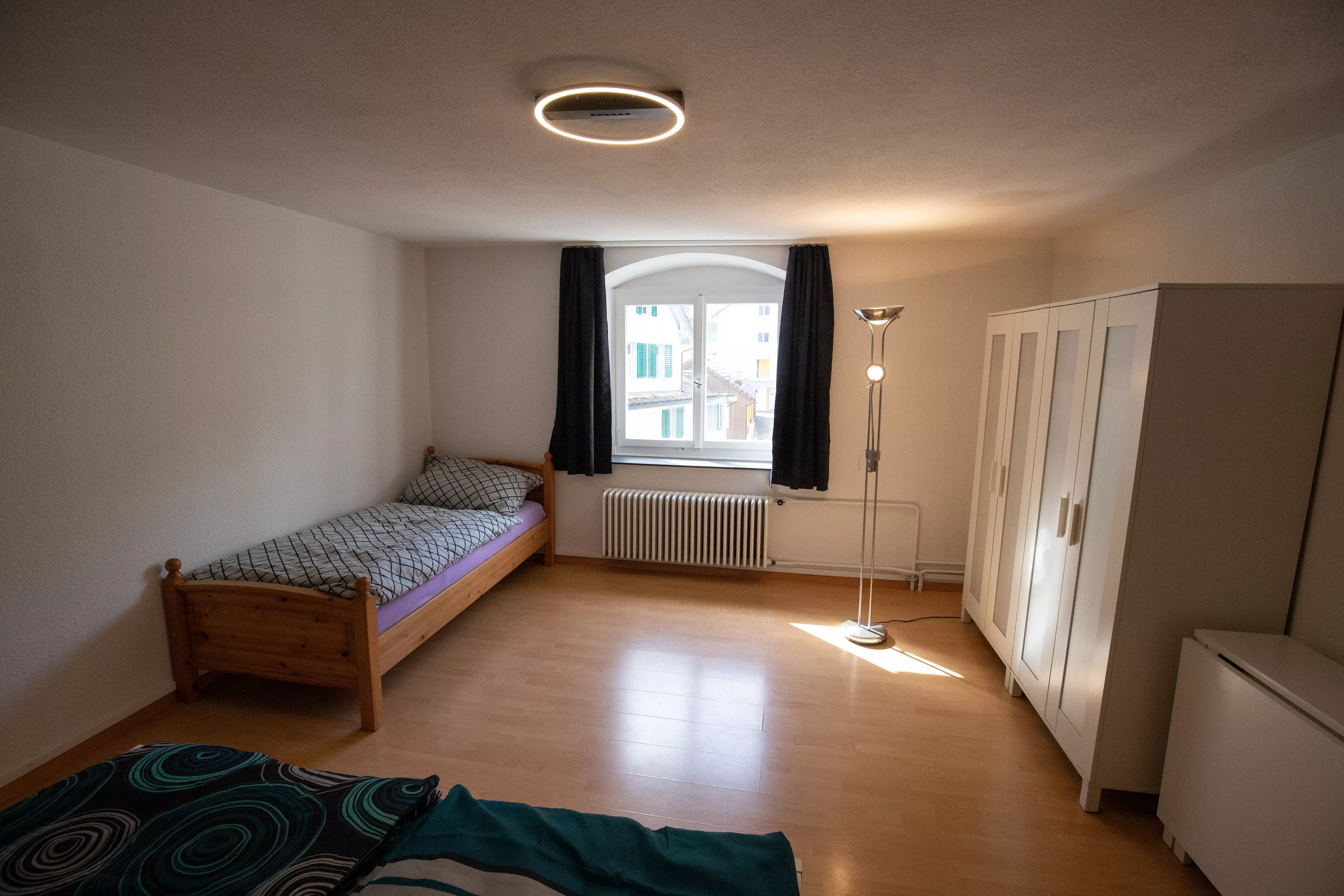 Helles Zimmer mit Einzelbett, grossem Fenster, Kleiderschrank und viel freiem Platz
