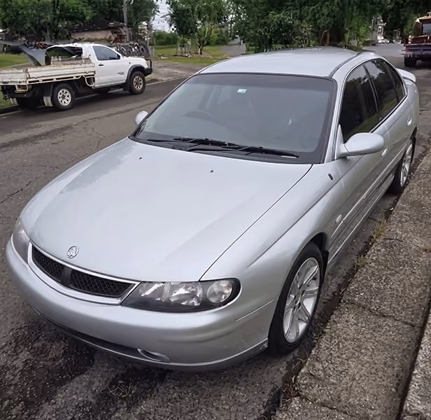 Older silver car parked by the roadside, ideal for unwanted car removal.