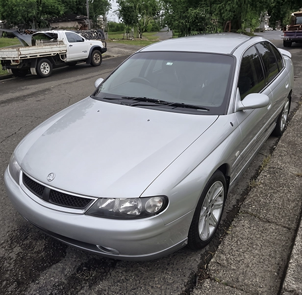 Older silver car parked by the roadside, ideal for unwanted car removal.