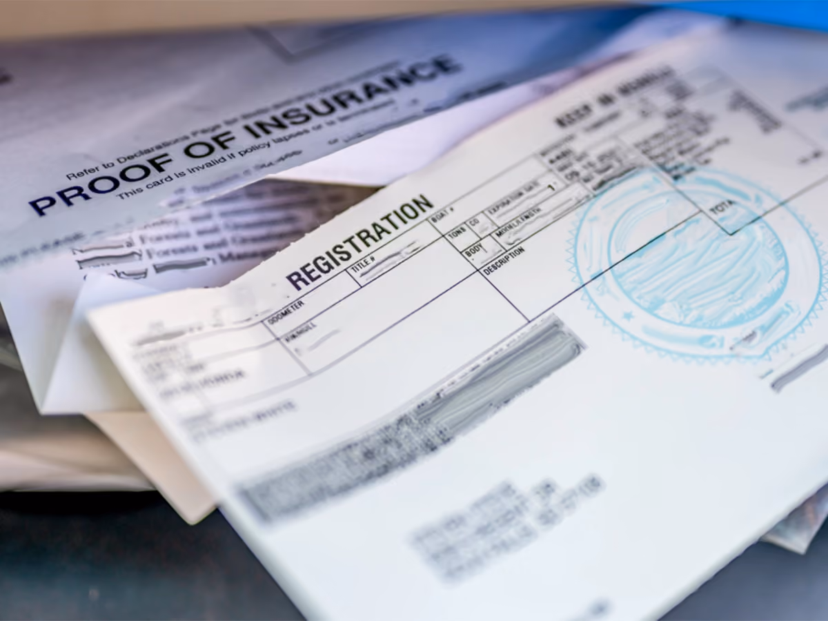Car paperwork showing registration details and insurance documents.