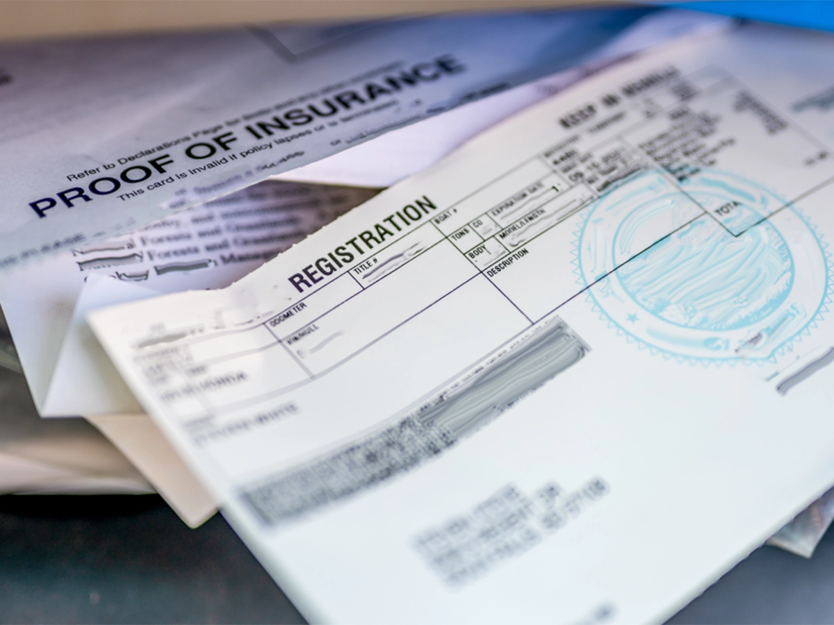 Car paperwork showing registration details and insurance documents.