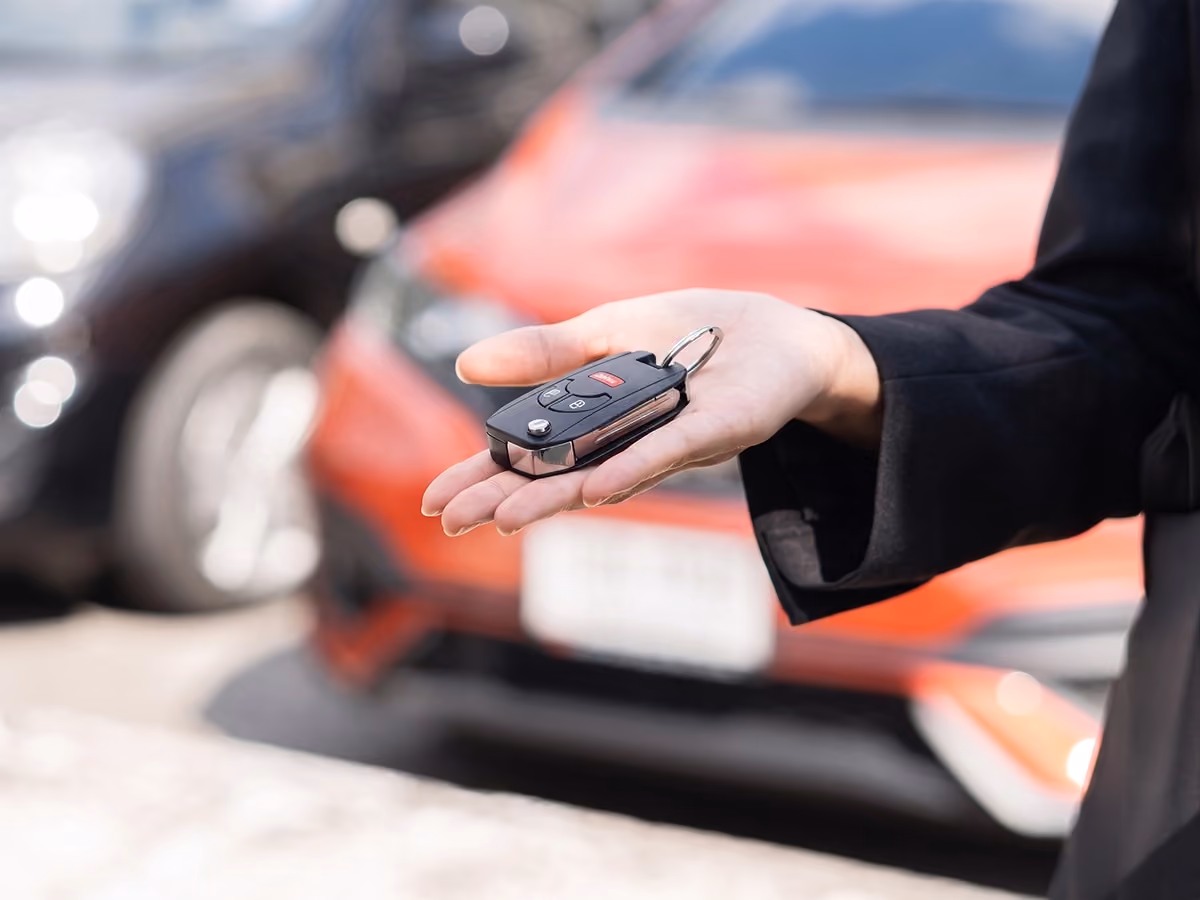 Close-up of car keys being handed over, showing the process of selling a vehicle.