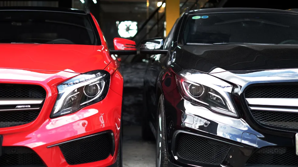 Two parked cars side by side in a garage, representing vehicles for sale.