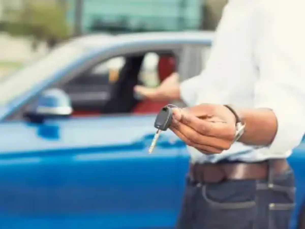 Close-up of a person holding a pen to sign an authorisation letter on a clipboard, with a car key fob resting on the paperwork.