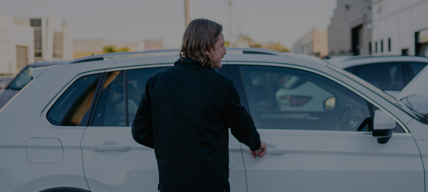 Person in black jacket standing next to white SUV in parking lot