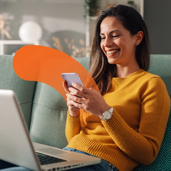 A smiling woman in a mustard-yellow sweater sits on a couch, holding and looking at her smartphone, with a laptop open in front of her. Beside her is a circular logo that reads “Osko by BPAY” over an orange abstract shape.