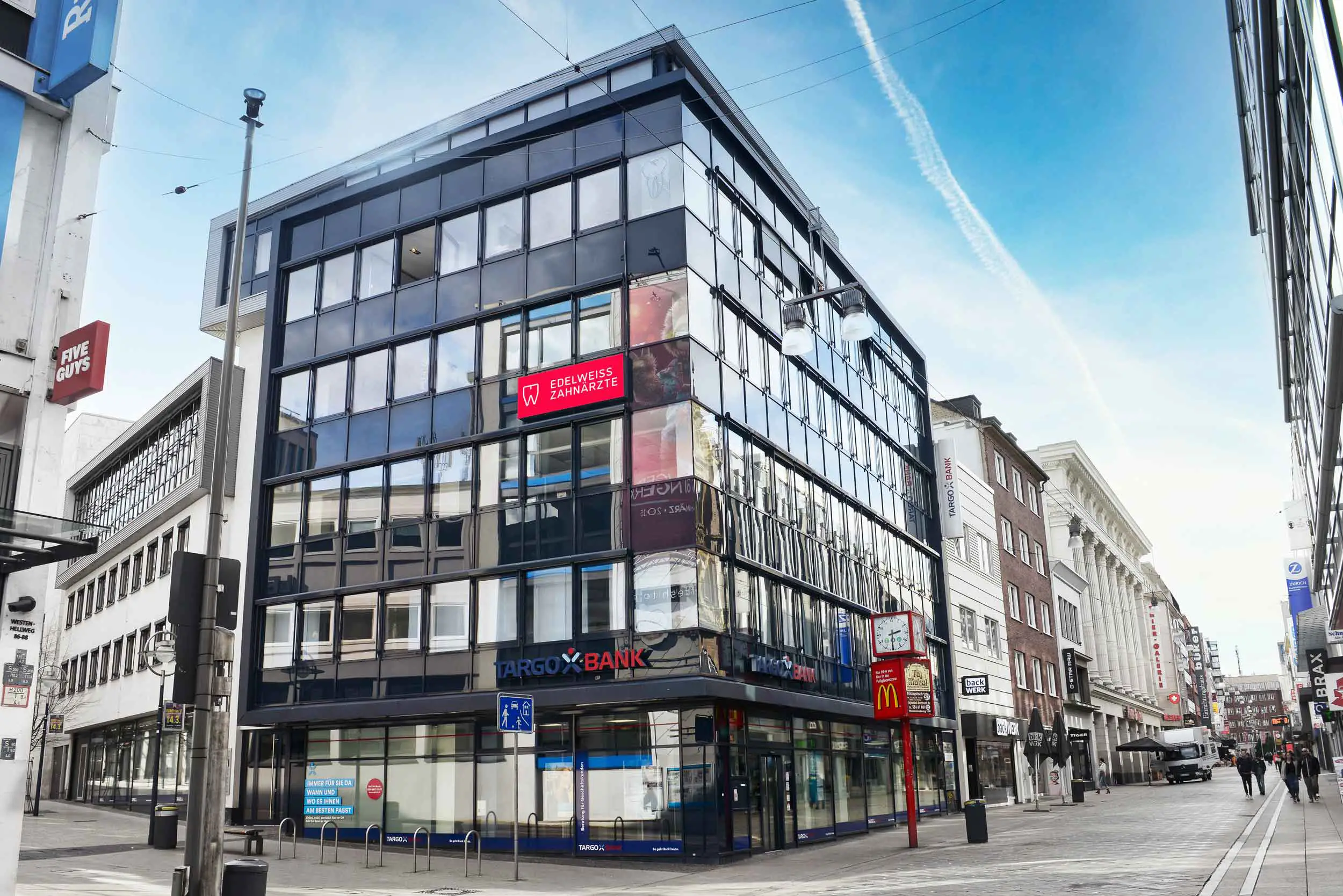 Ein modernes Gebäude mit vielen Fenstern an einer städtischen Straße.