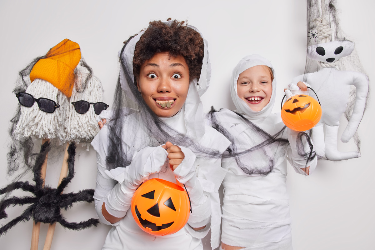 Happy, positive woman and child pose with Halloween costumes