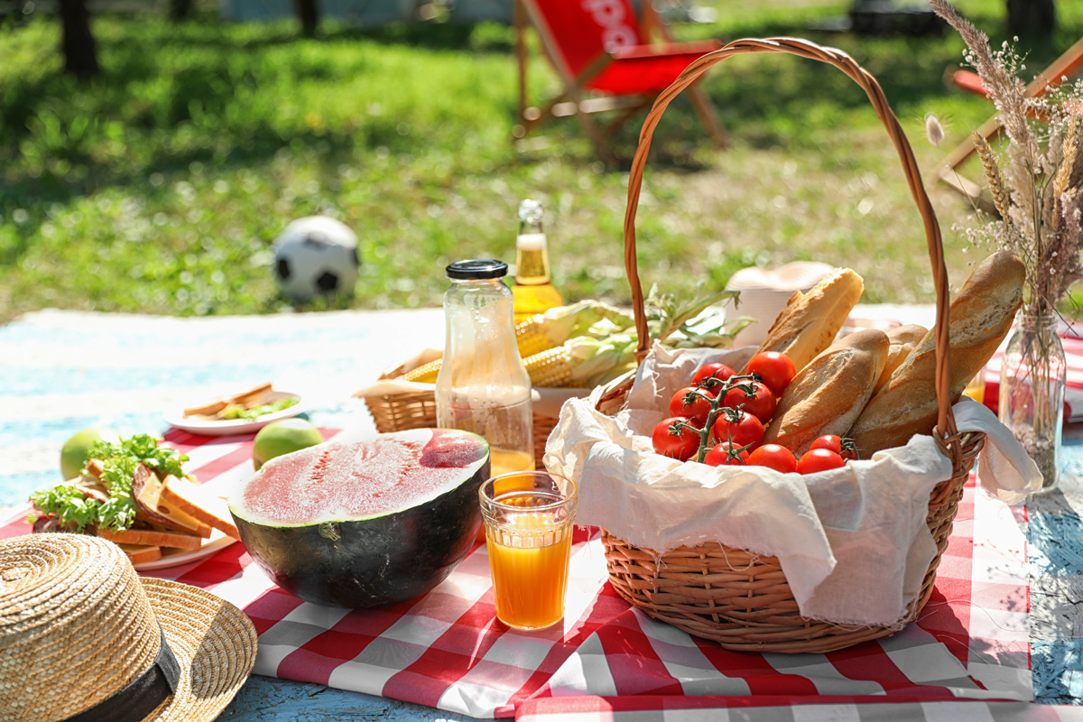 An assortment of picnic foods spread out on blanket on the grass