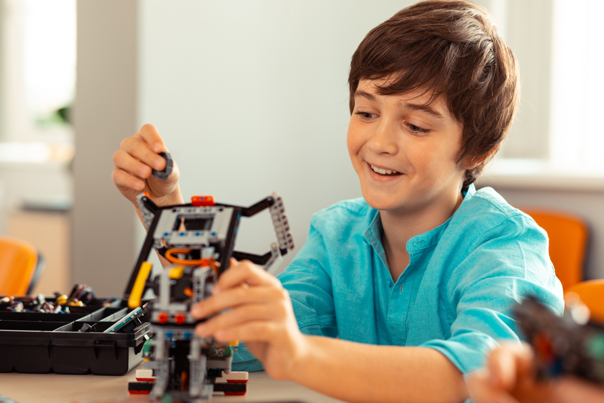 Enthusiastic young boy working with legos in a classroom