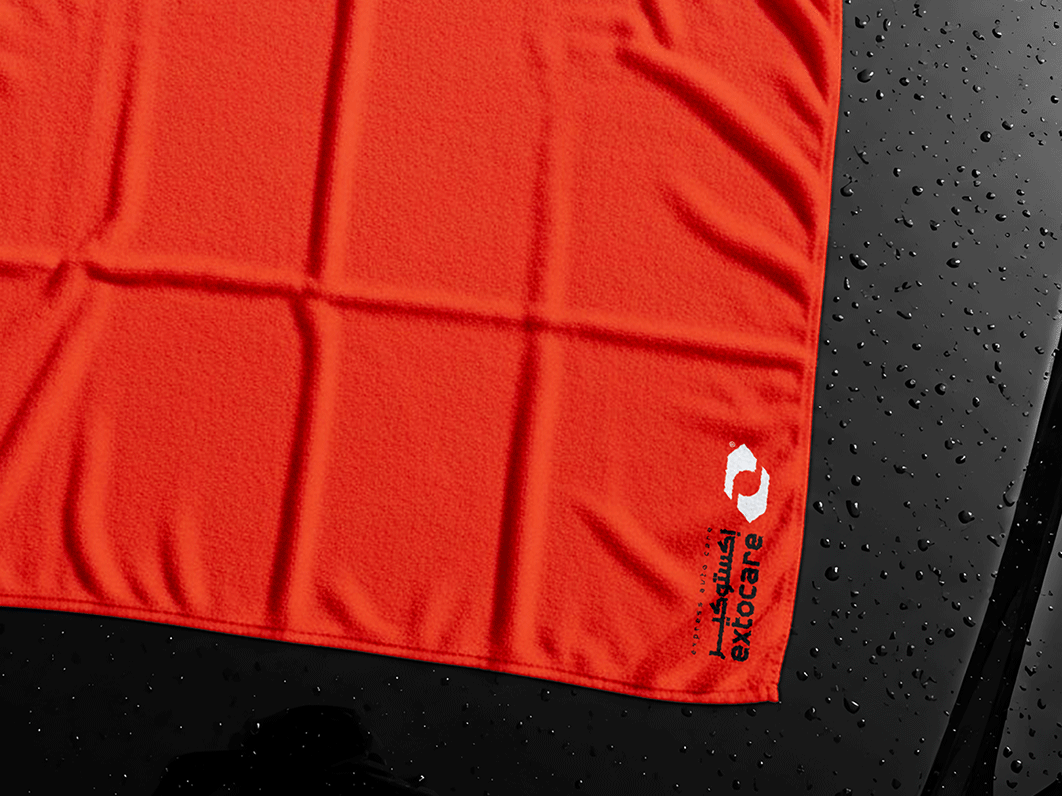 Close-up of an orange hoodie with drawstrings, showing a black inner label with the letter “A.”