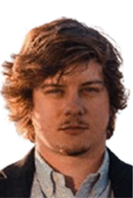 Jeune homme aux cheveux bruns bouclés portant une chemise claire et une veste sombre.