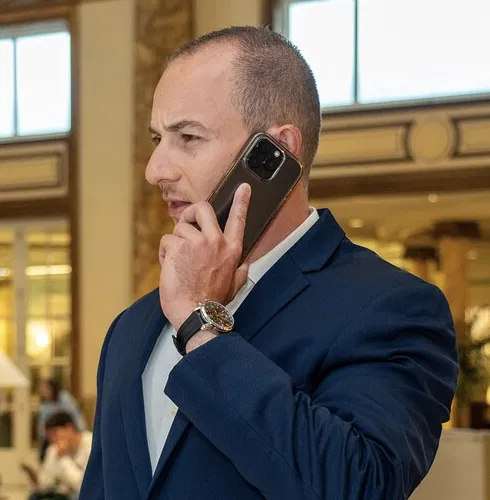 Homme en costume bleu parlant au téléphone portable dans un intérieur élégant.