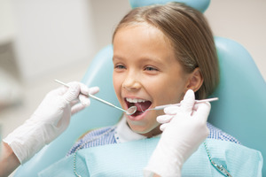 Little girl having teeth examined by dentist