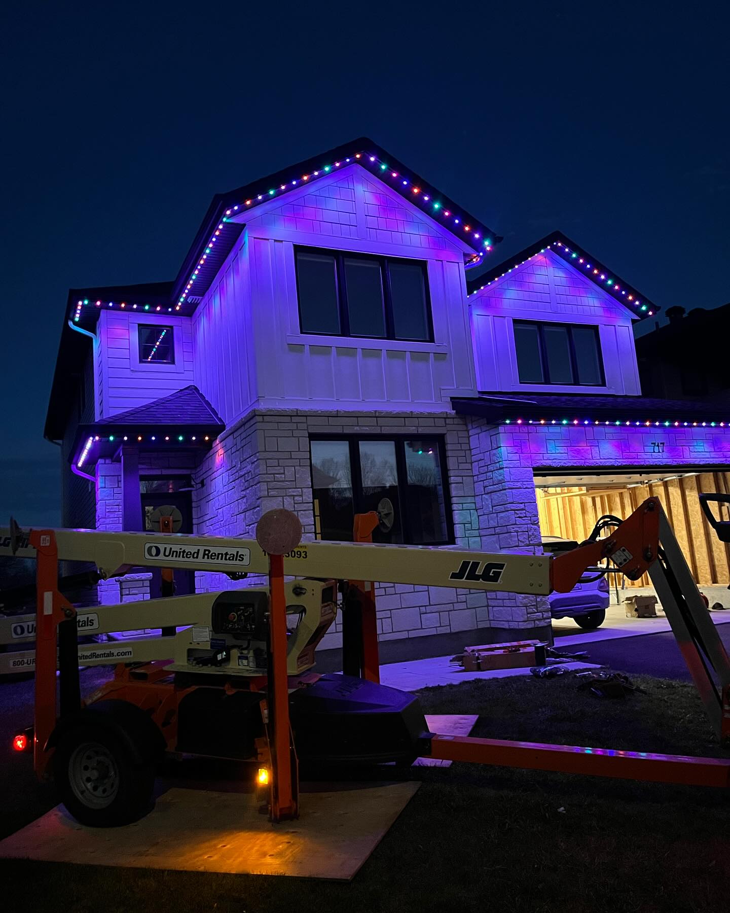 Multicolour permanent LED soffit lighting installed on new construction home by RoyalShine Lighting in the GTA, showcasing customizable RGB exterior lighting during installation with lift equipment