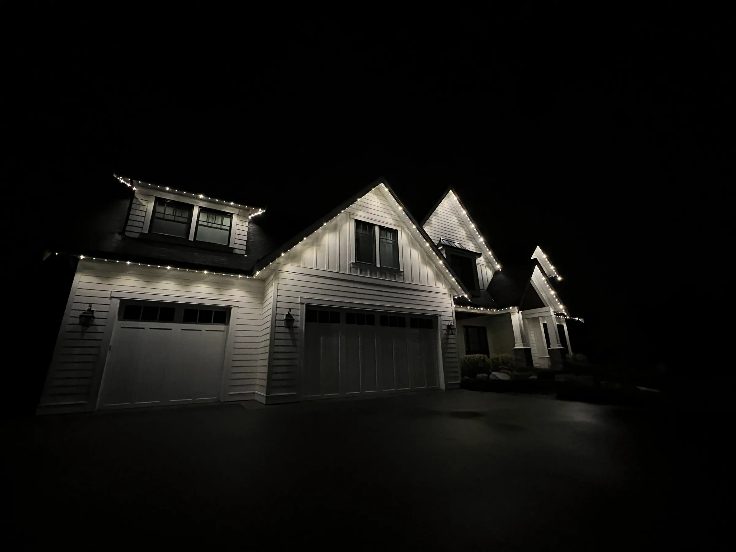 White permanent lighting on a home with vertical siding