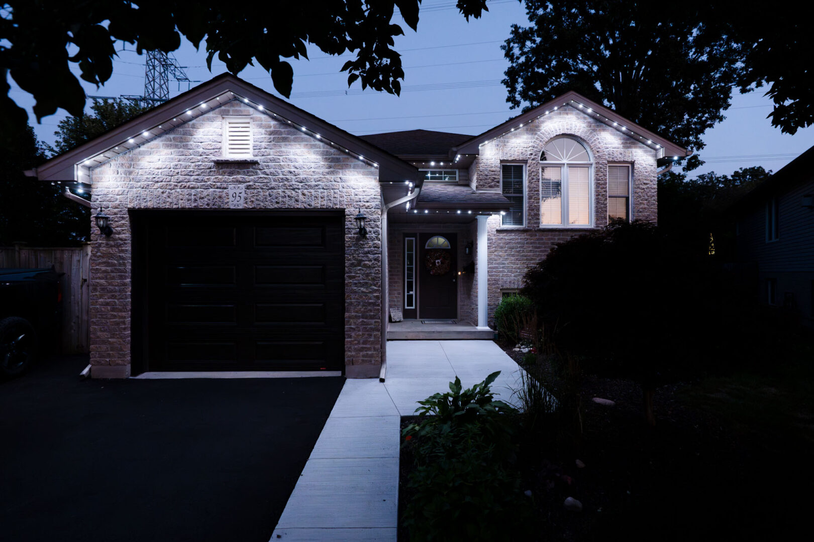 White permanent lighting on a brick raised bungalow