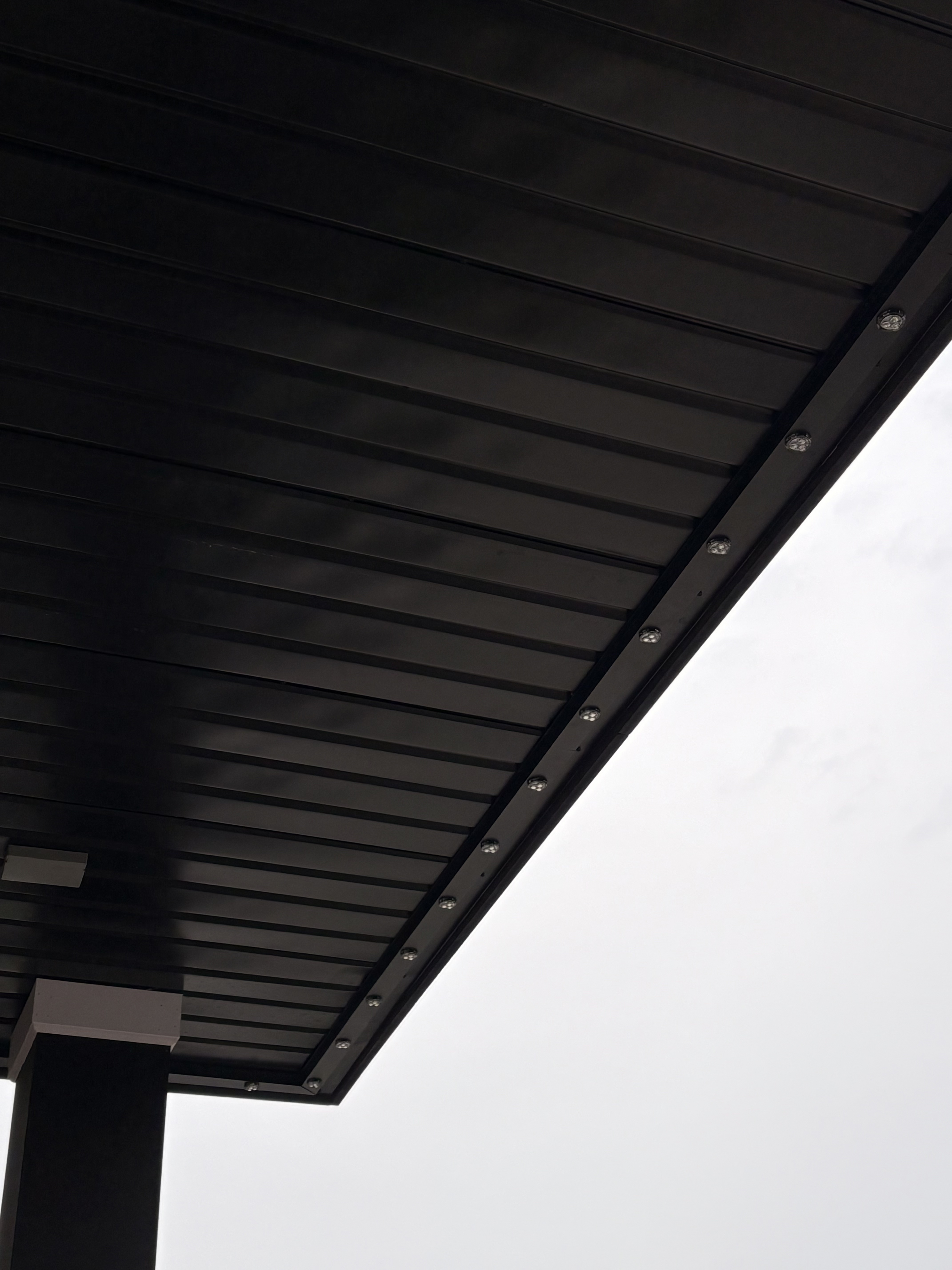 Close-up of dark permanent LED track mounted beneath a soffit
